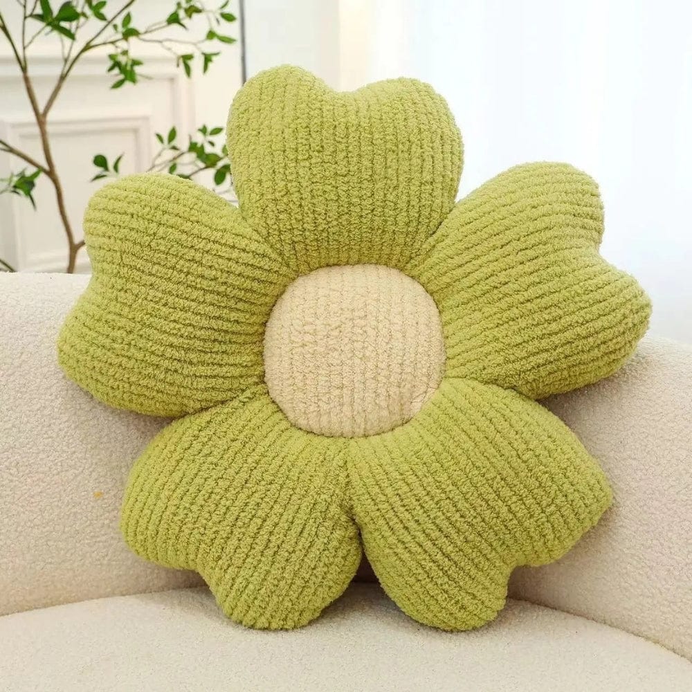 Coussin décoratif en forme de fleur, vert avec un centre beige, posé sur un canapé clair