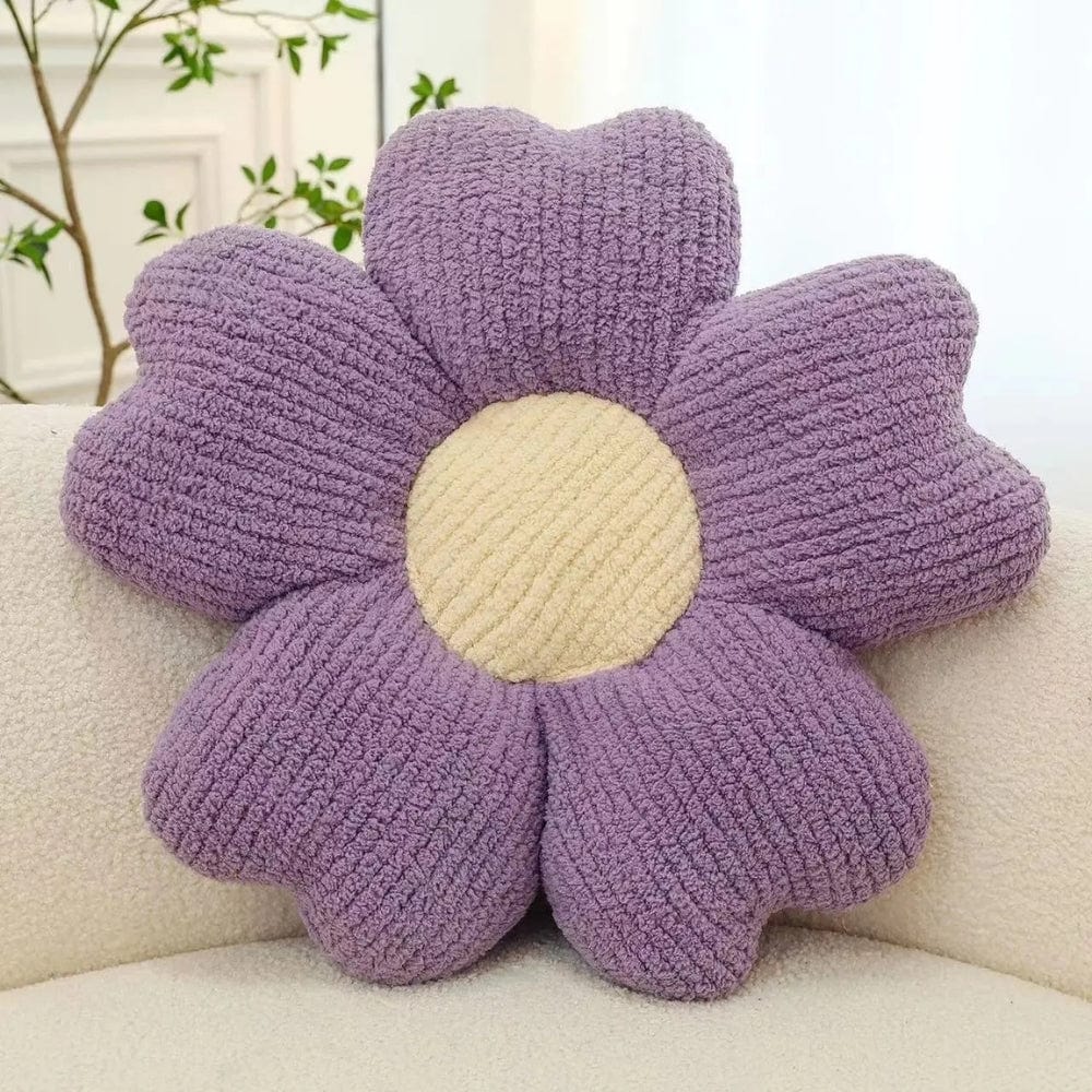 Coussin décoratif en forme de fleur, violet et beige, posé sur une banquette douce et moderne