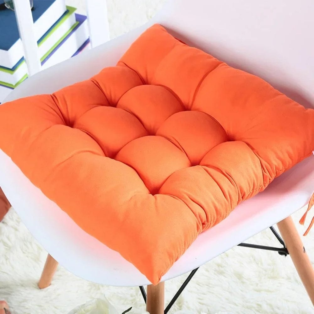 Coussin de chaise de jardin en tissu orange, rembourré avec des motifs matelassés, posé sur une chaise blanche