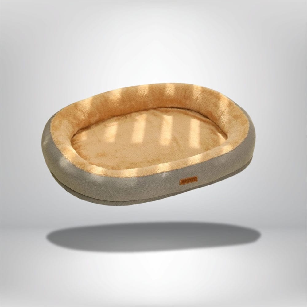 Coussin décoratif ovale en velours beige et marron, idéal pour un chat, posé sur un fond neutre