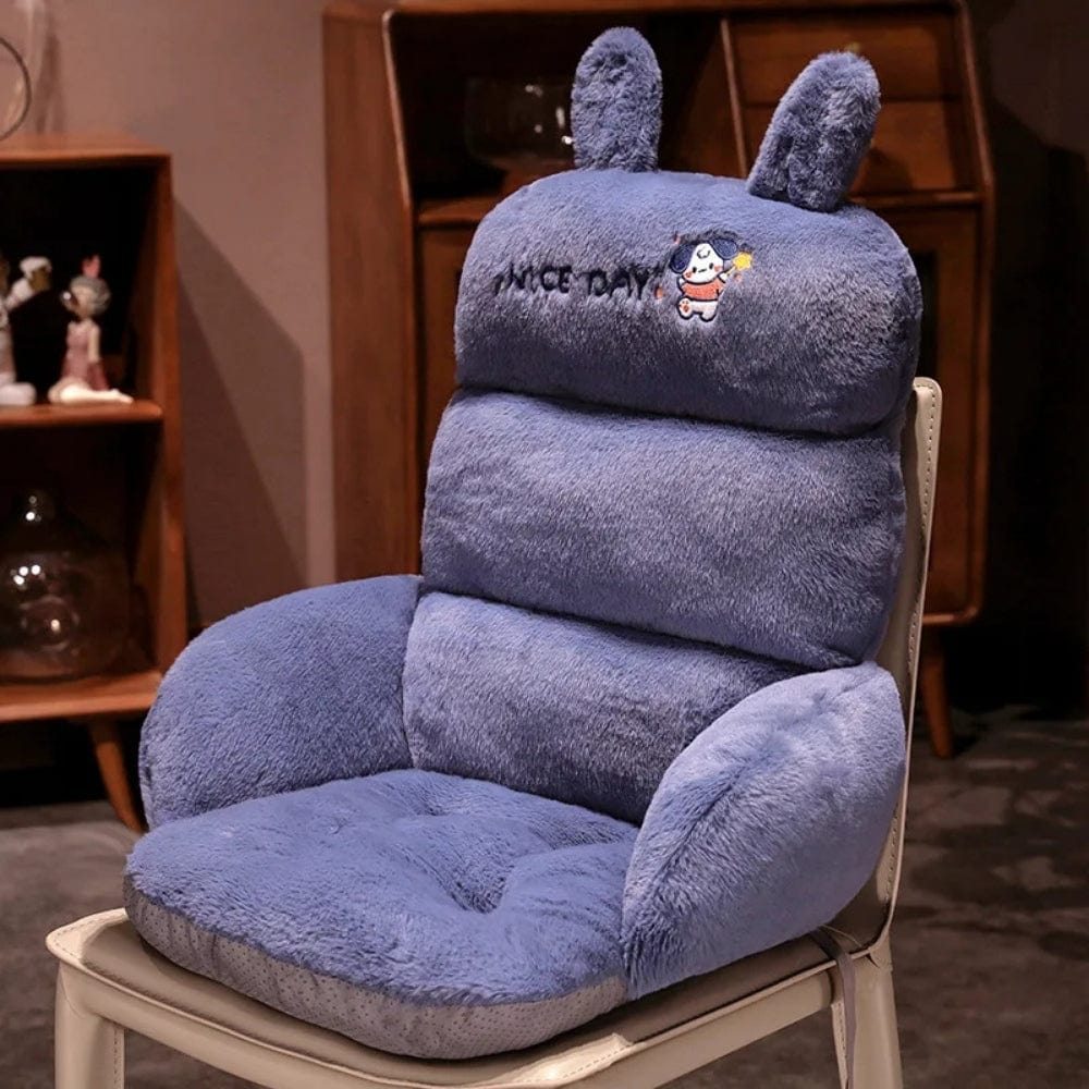 Coussin décoratif en velours bleu avec oreilles de lapin, posé sur un fauteuil moderne dans un salon chaleureux