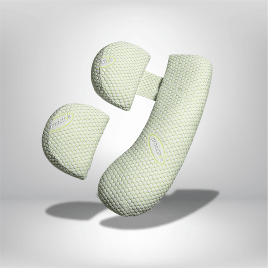 Coussin de grossesse en forme ergonomique, couleur vert pâle avec texture alvéolée, posé sur un fond neutre