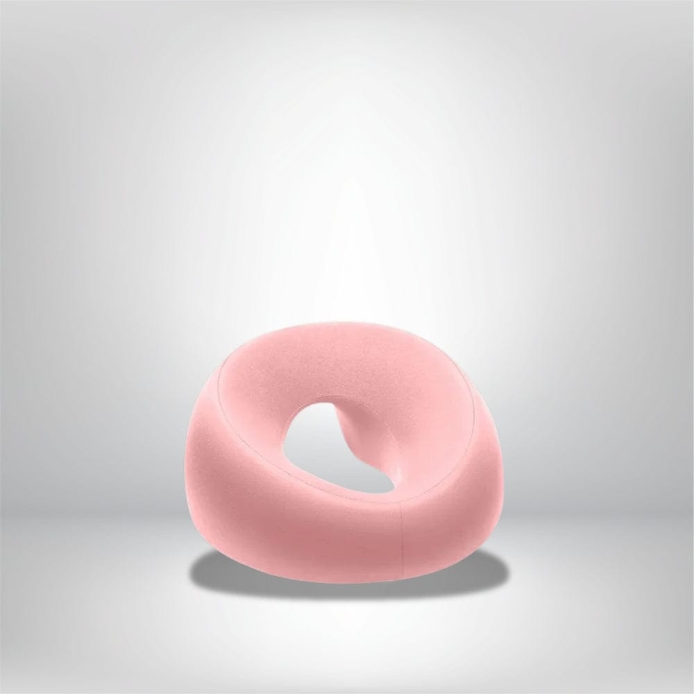 Coussin de massage en velours rose, en forme de donut, sur fond gris clair, idéal pour le confort