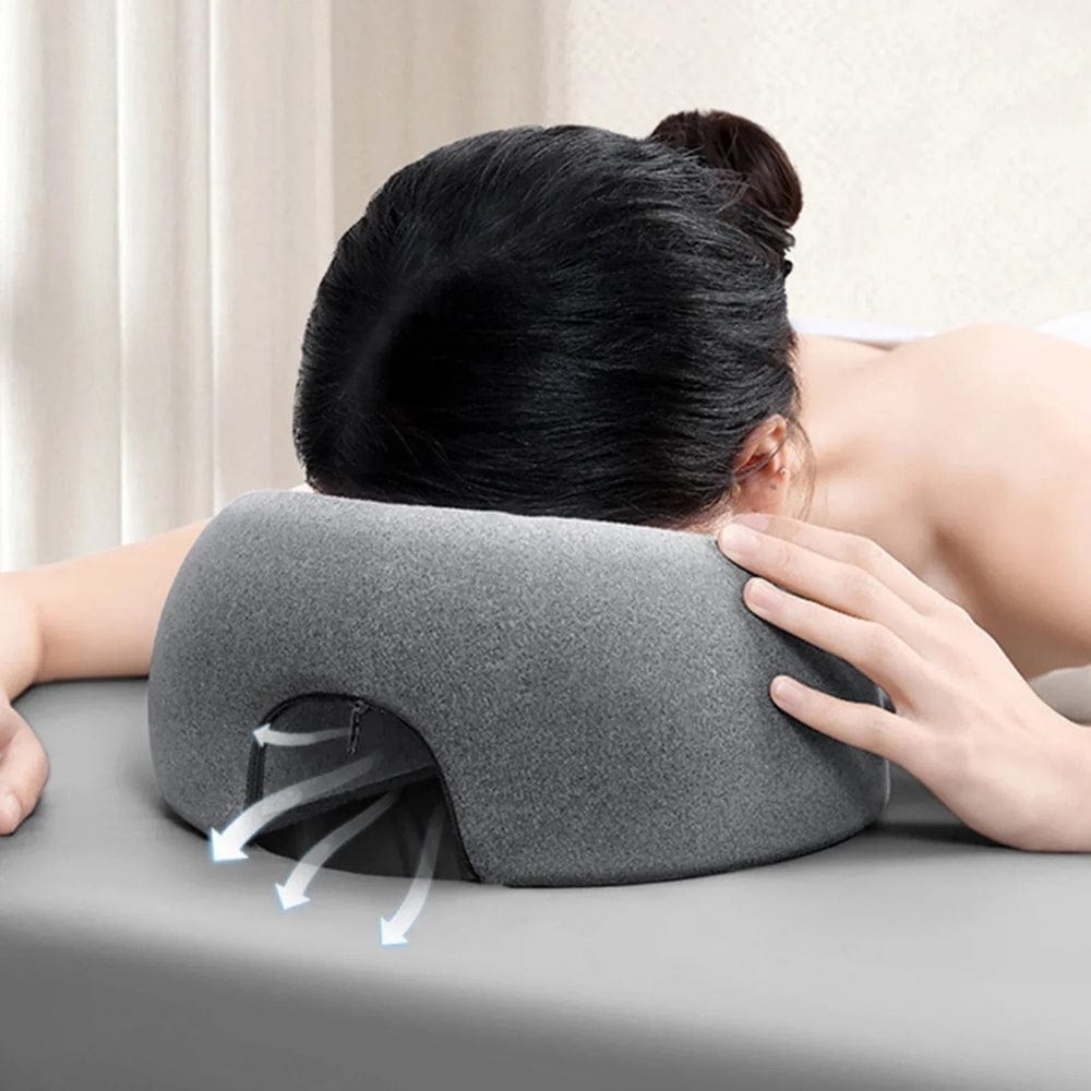 Coussin de massage gris en velours, placé sur une table, offrant un soutien confortable pour la tête