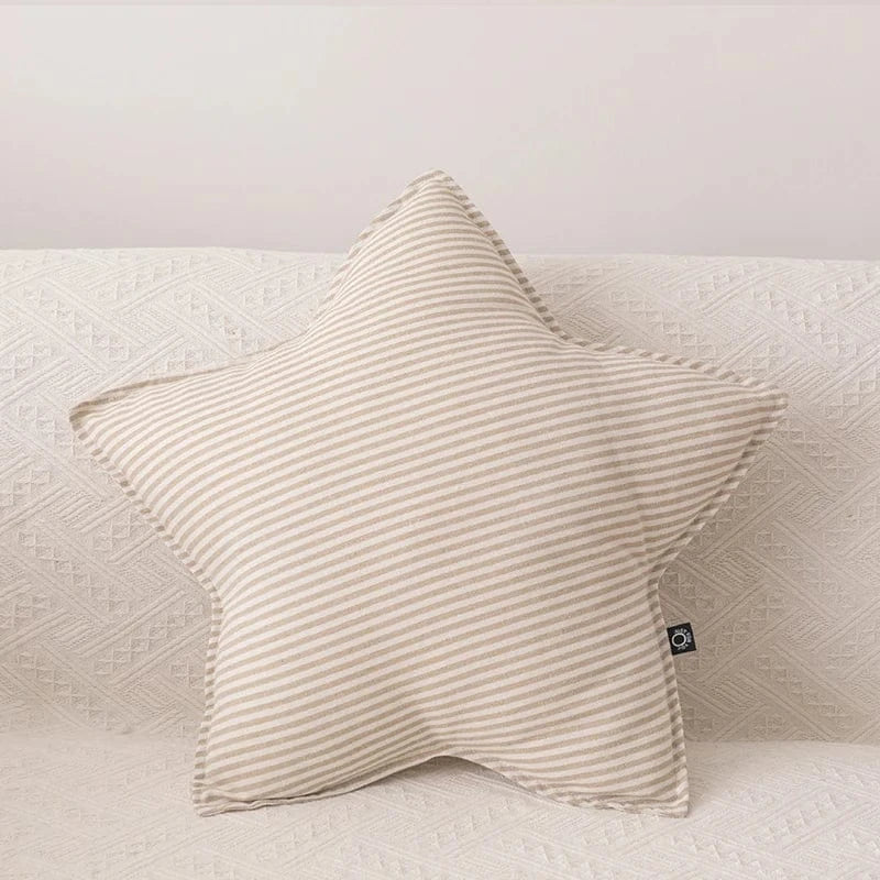 Coussin décoratif en forme d'étoile, rayé beige, posé sur un canapé clair et texturé