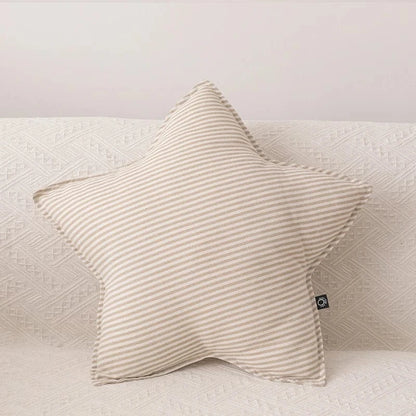 Coussin décoratif en forme d'étoile, rayé beige, posé sur un canapé clair et texturé