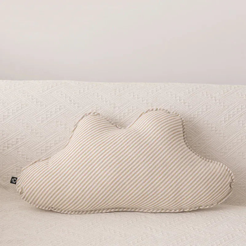 Coussin décoratif en forme de nu, rayé beige et blanc, posé sur un canapé texturé