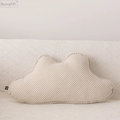 Coussin décoratif en forme de nu, rayé beige et blanc, posé sur un canapé texturé