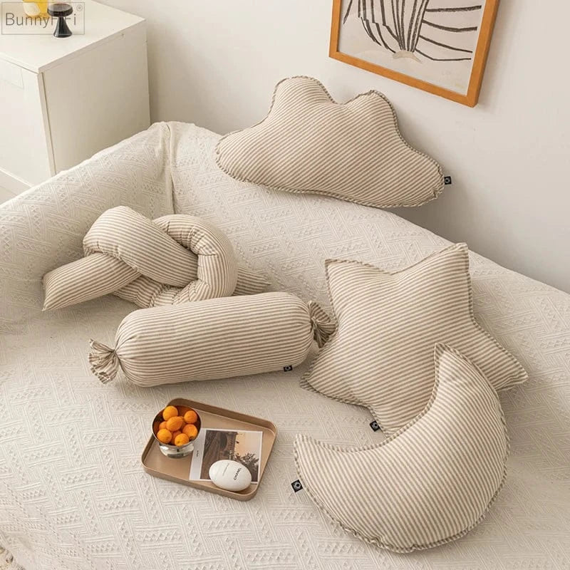 Coussins décoratifs rayés en beige et blanc disposés sur un canapé, créant une ambiance chaleureuse et moderne