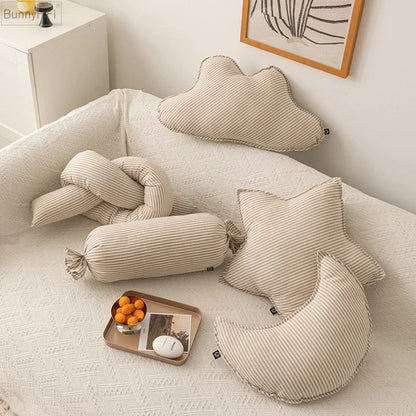 Coussins décoratifs rayés en beige et blanc disposés sur un canapé, créant une ambiance chaleureuse et moderne