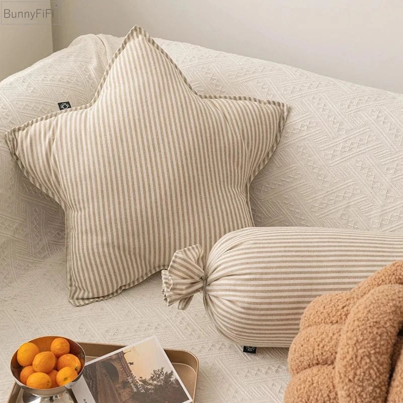 Coussin décoratif en forme d'étoile à rayures beiges sur un canapé aux textures douces