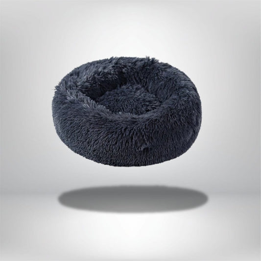 Coussin rond en fausse fourrure gris foncé, idéal pour un chat, posé sur un fond neutre