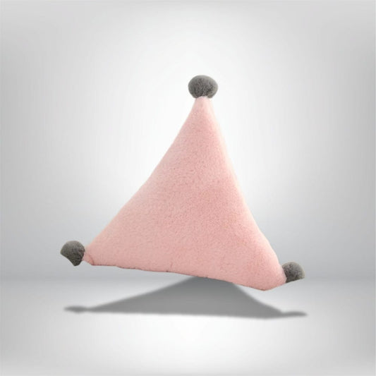 Coussin déco triangulaire en velours rose pâle avec pompons gris, posé sur un fond neutre