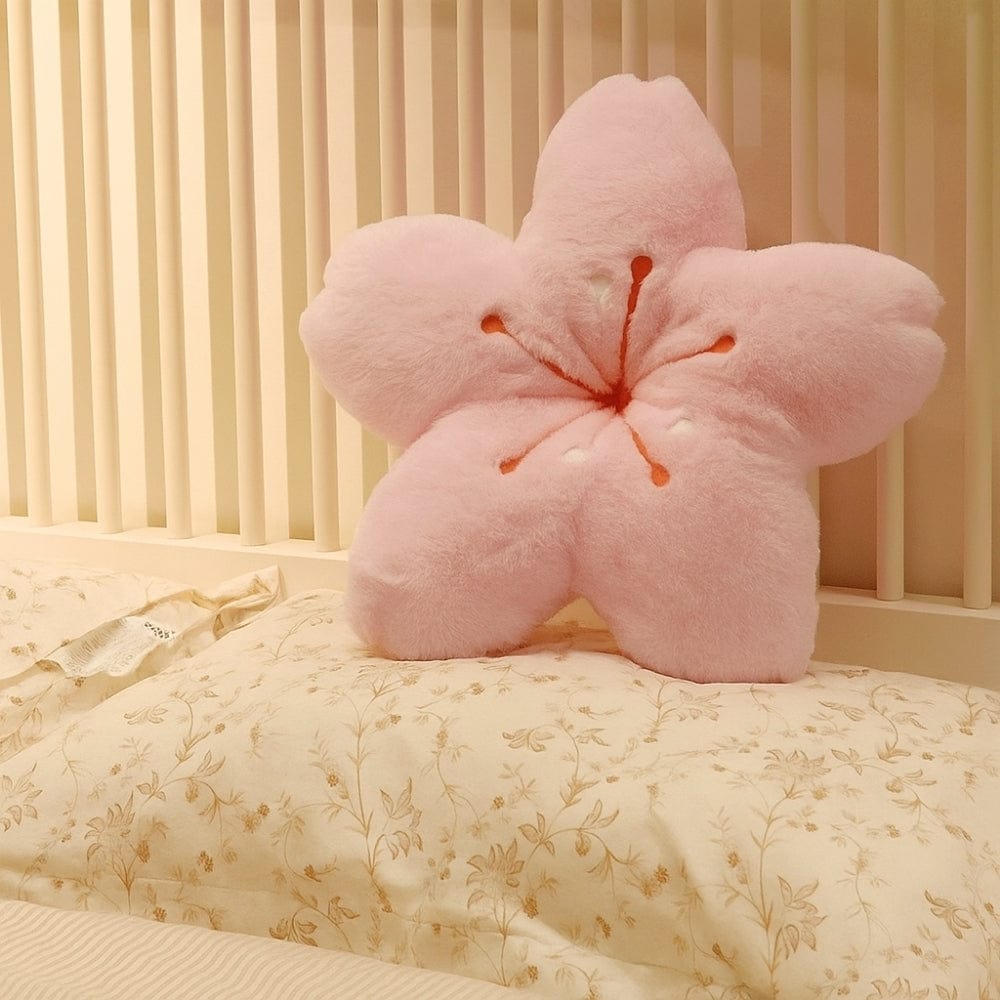 Coussin décoratif en forme de fleur, rose poudre, posé sur un lit avec des draps à motifs floraux