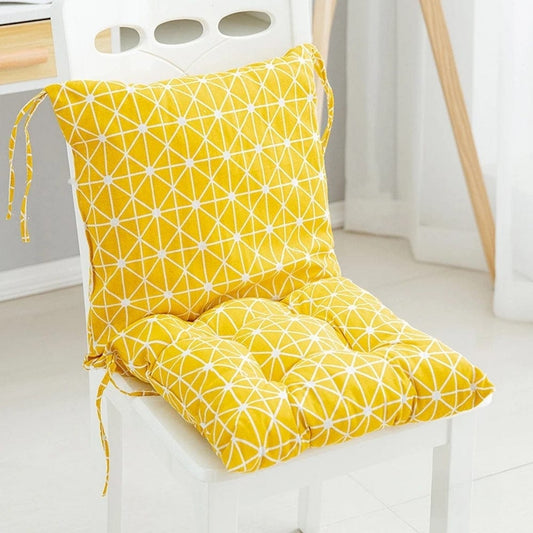 Coussin décoratif jaune à motifs géométriques blancs sur une chaise dans un intérieur moderne