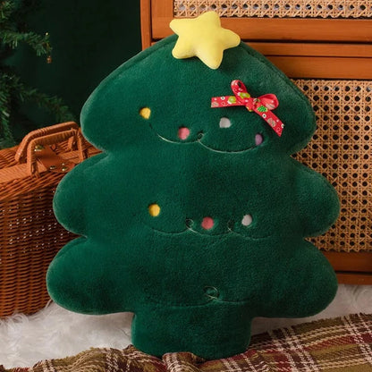 Coussin décoratif en forme de sapin de Noël vert, avec étoile jaune et décorations colorées, sur un plaid dans un