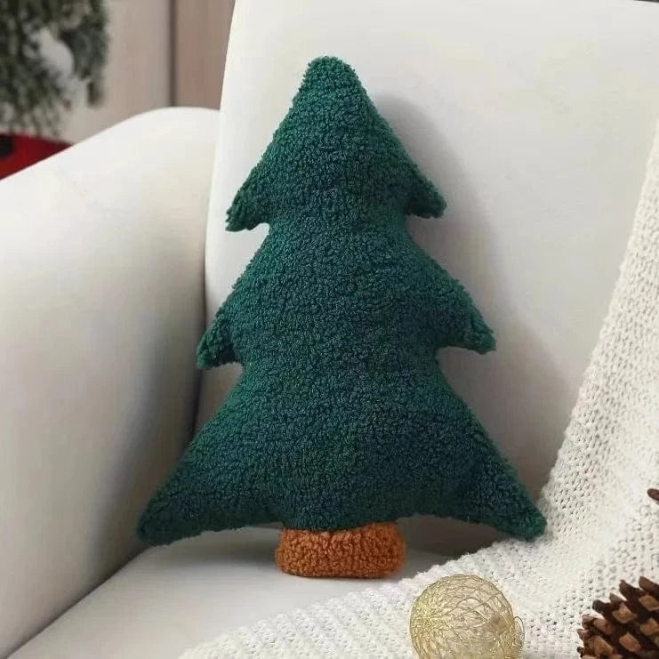 Coussin en forme de sapin vert en tissu doux, posé sur un canapé blanc, ajoutant une touche festive