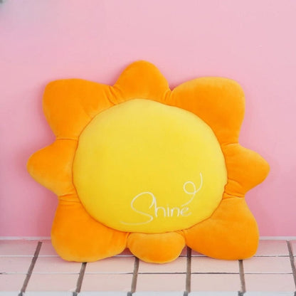 Coussin décoratif en forme de soleil, jaune et orange, posé sur un fond rose, idéal pour un canapé
