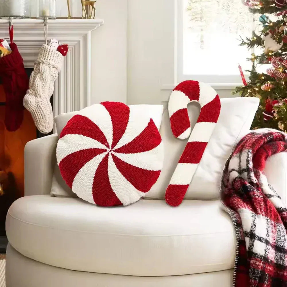 Coussin décoratif rond aux motifs spirales rouges et blancs, posé sur un canapé blanc dans un salon chaleureux