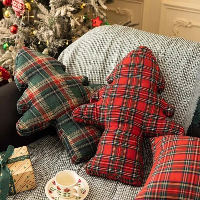 Coussins décoratifs en tartan rouge et vert, en forme d'arbre, sur un canapé cosy pour une ambiance festive