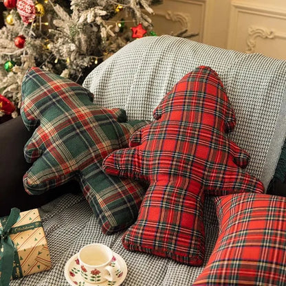 Coussins décoratifs en tartan rouge et vert, en forme d'arbre, sur un canapé cosy pour une ambiance festive