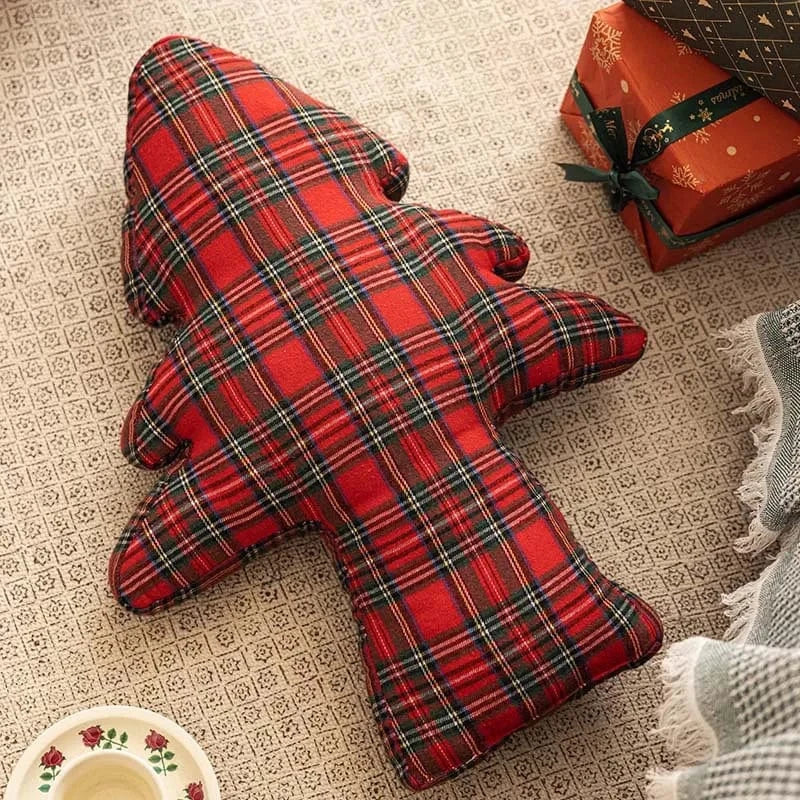 Coussin décoratif en tartan rouge et noir, en forme d'arbre, posé sur un tapis dans un salon chaleureux