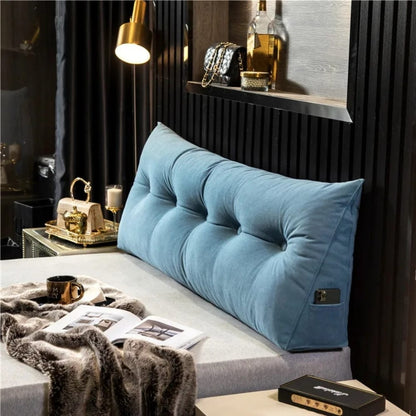 Coussin déco en velours bleu, forme géante et capitonnée, placé sur un lit moderne avec des accessoires dorés