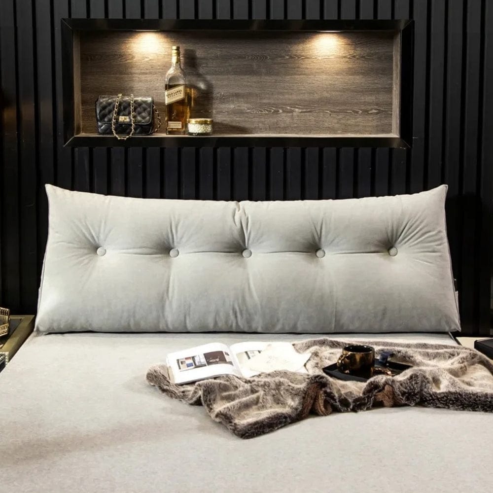 Coussin déco en velours gris clair, forme géante avec boutons, posé sur un lit moderne avec couverture douce