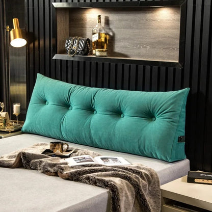 Coussin décoratif en velours vert turquoise, forme allongée avec boutons, posé sur un lit moderne avec une couverture douce