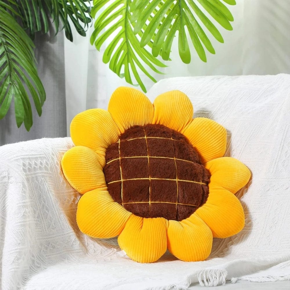 Coussin décoratif en forme de tournesol jaune avec un centre marron, posé sur un canapé blanc