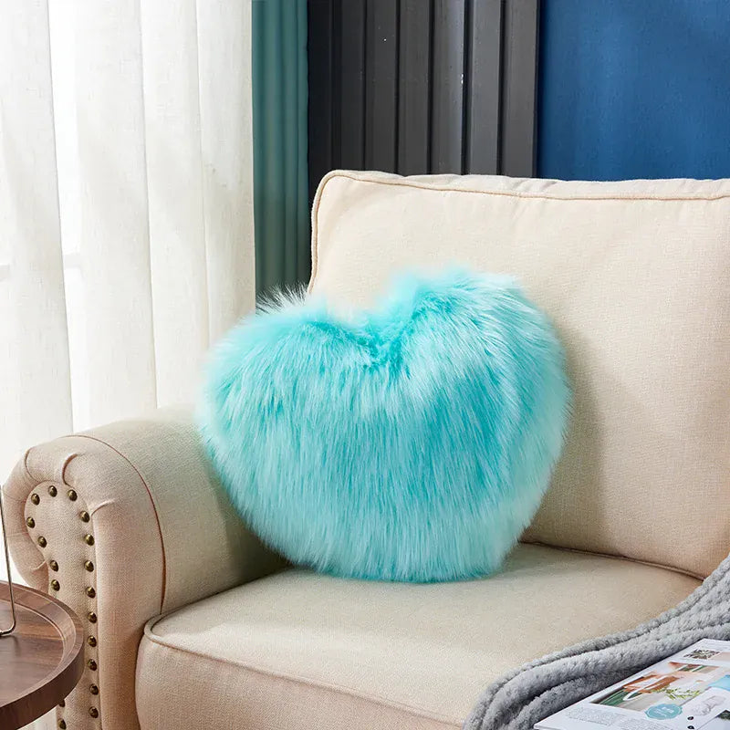 Coussin décoratif en moumoute turquoise en forme de cœur posé sur un canapé beige dans un salon moderne