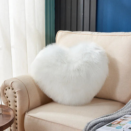 Coussin décoratif en forme de cœur, en moumoute blanche, posé sur un canapé beige dans un salon lumineux