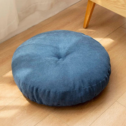 Coussin pouf rond en tissu bleu, posé sur un sol en bois, apportant une touche déco moderne au salon