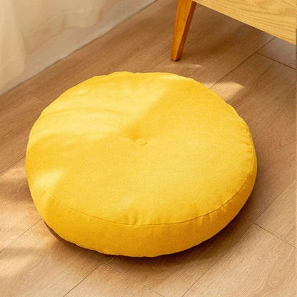 Gros coussin pouf rond jaune en tissu, posé sur un sol en bois, idéal pour une décoration moderne
