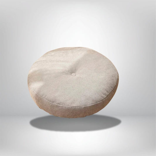 Gros coussin pouf rond en tissu beige, posé sur un fond neutre, idéal pour un salon ou une chambre