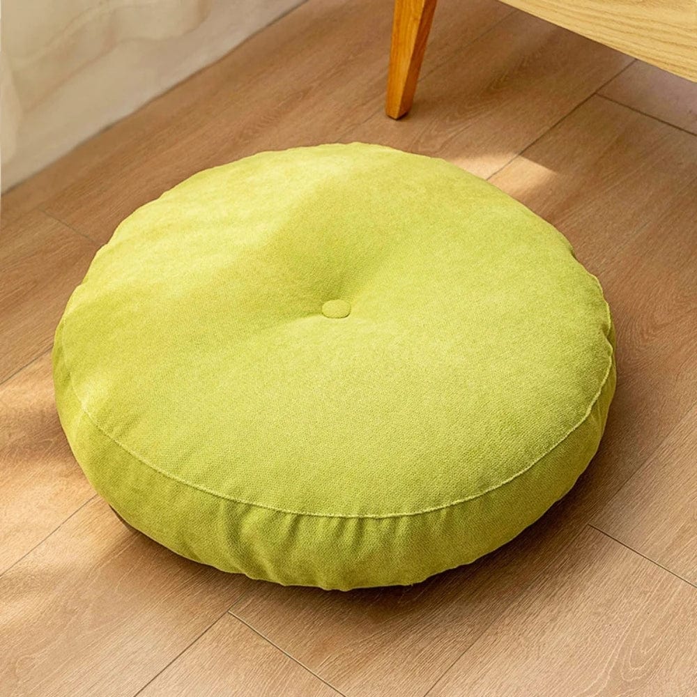 Coussin pouf rond en tissu vert, posé sur un sol en bois, idéal pour un salon ou une chambre