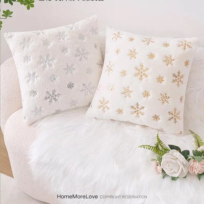 Coussins décoratifs en fausse fourrure blanche avec motifs flocons de neige argentés et dorés sur un canapé