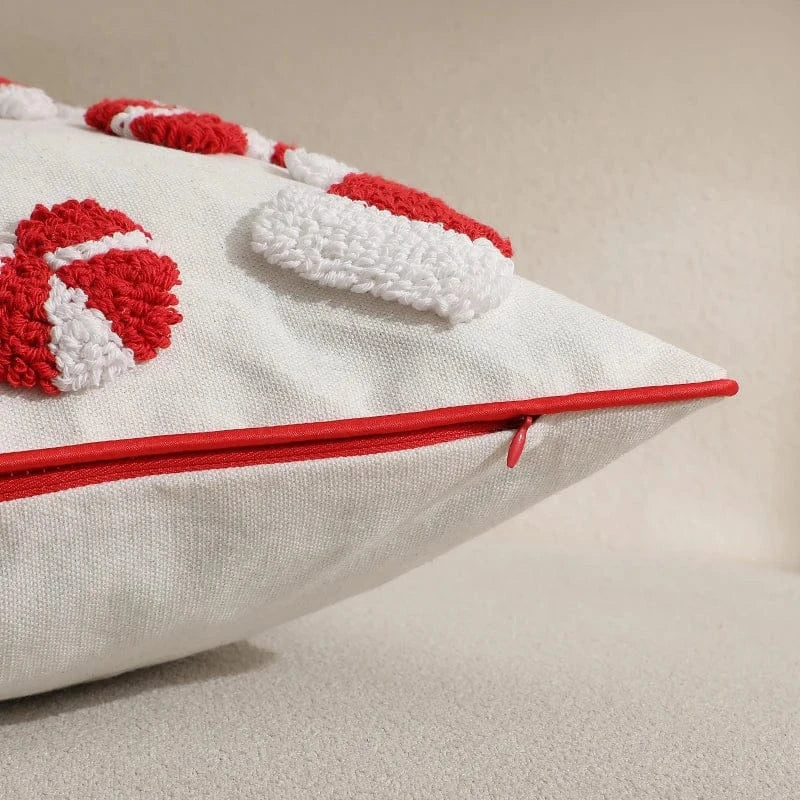 Housse de coussin décoratif blanche avec motifs rouges en relief, posée sur un canapé beige