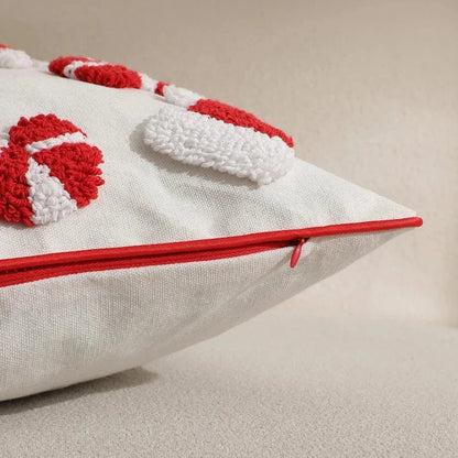 Housse de coussin décoratif blanche avec motifs rouges en relief, posée sur un canapé beige