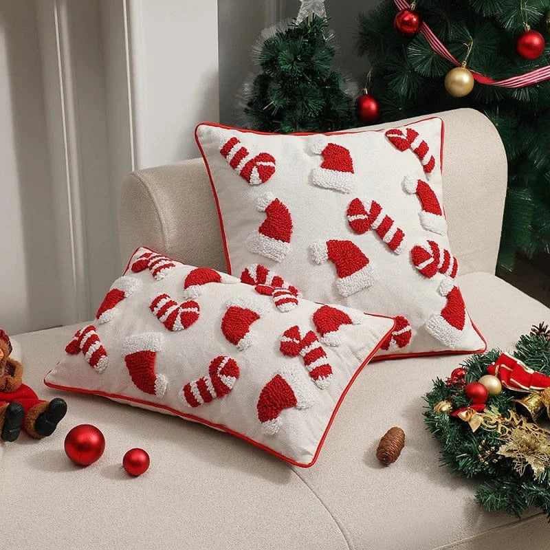 Housse de coussin décorative blanche avec motifs de bonnets de Noël rouges sur un canapé beige