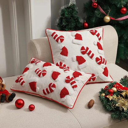 Housse de coussin décorative blanche avec motifs de bonnets de Noël rouges sur un canapé beige