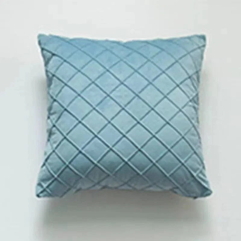 Coussin déco en velours bleu avec motif losanges, posé sur un fond neutre, idéal pour un salon élégant