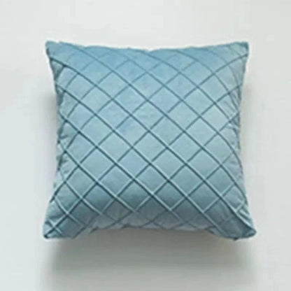 Coussin déco en velours bleu avec motif losanges, posé sur un fond neutre, idéal pour un salon élégant