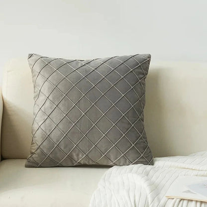 Coussin décoratif en velours gris avec motif losanges, posé sur un canapé clair dans un salon élégant