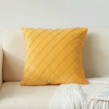 Coussin décoratif jaune en velours avec un motif en losanges, posé sur un canapé beige élégant