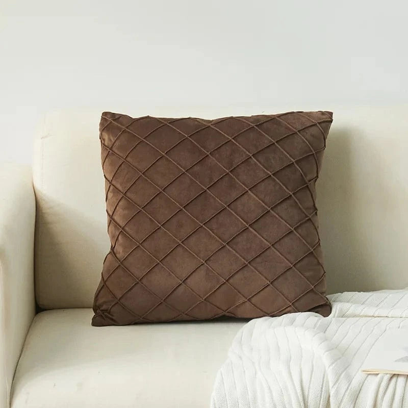 Coussin déco en velours marron à motif losanges, posé sur un canapé clair dans un intérieur moderne