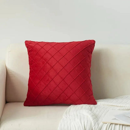 Coussin décoratif en velours rouge avec motif losanges, posé sur un canapé beige, apportant une touche élégante à l'intérieur