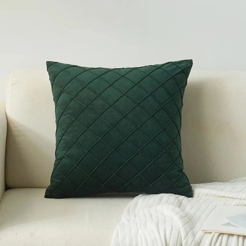 Coussin décoratif en velours vert avec motif losange, posé sur un canapé beige dans un salon élégant