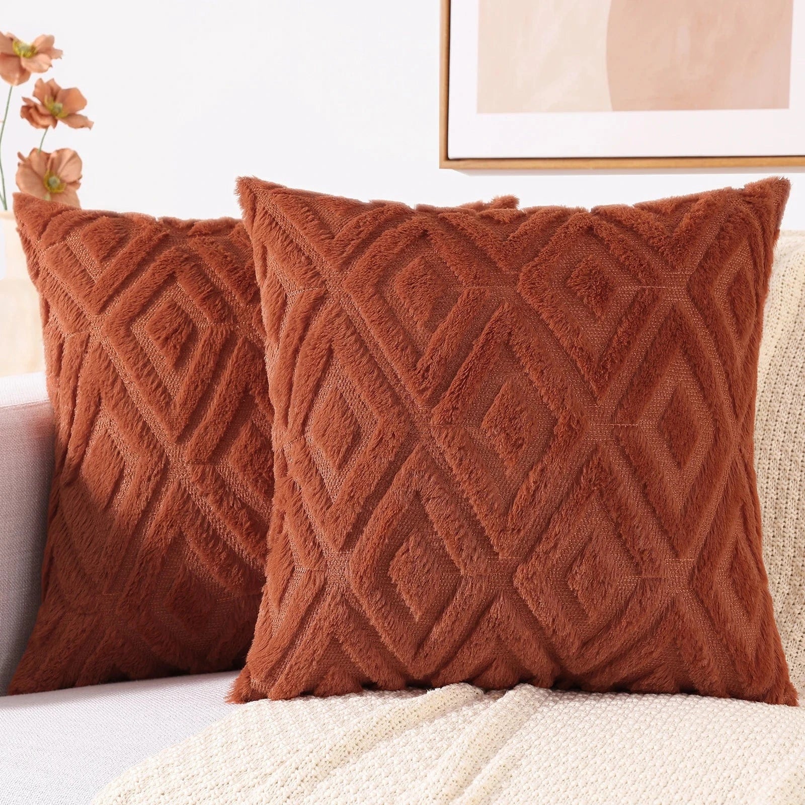 Coussins décoratifs en velours doux couleur terracotta avec motifs géométriques, posés sur un canapé moderne