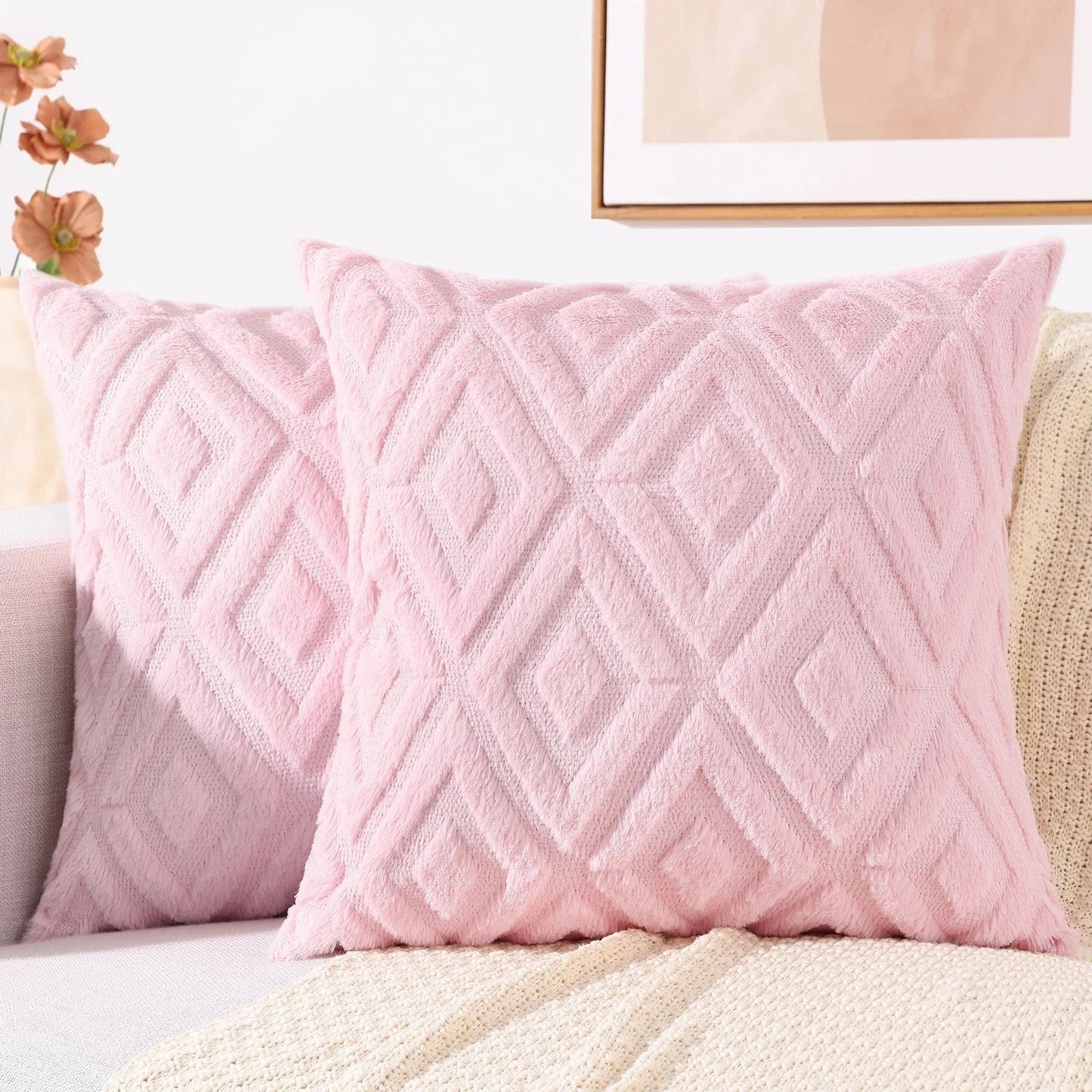 Coussins décoratifs en velours rose avec motifs géométriques, posés sur un canapé moderne et élégant